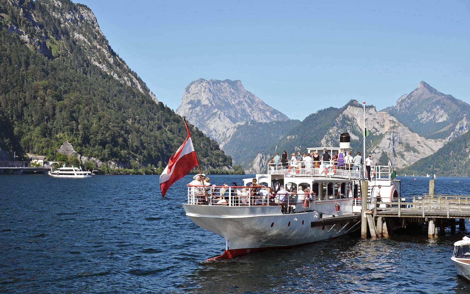 Ein Ausflugsschiff legt an einer Anlegestelle am Traunsee an. Auf dem Schiff befinden sich viele Touristinnen.