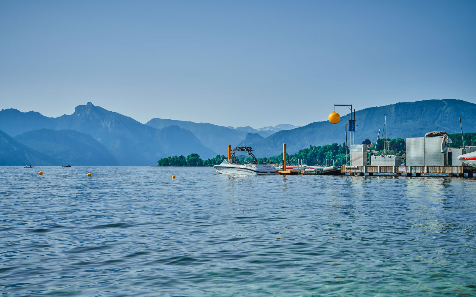 Die Markierung einer Start- und Landegasse für Wasserskisport. Gekennzeichnet durch gelbe Bojen im Wasser und einem gelben Ball beim Steg.